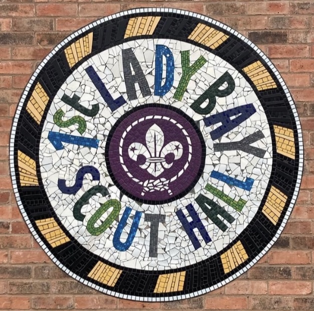 A round mural created from tile peices, spelling out 1st Lady Bay Scout Hall